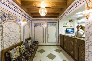 a man standing at a counter in a room with ornamental walls at Boutique Safiya in Bukhara