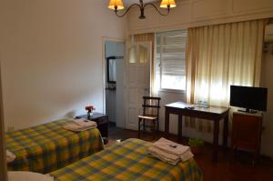 a room with two beds and a desk and a television at Hospedaje 371 in Salta