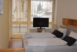ein Wohnzimmer mit einem Bett und einem Flachbild-TV in der Unterkunft Hotel Hages in Bad Salzuflen