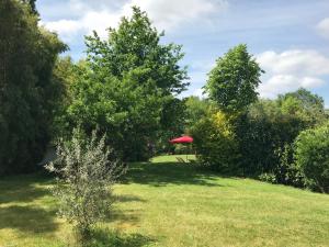 - un jardin avec un parasol rouge au milieu dans l'établissement Les Arbres Rouges, à Sucé-sur-Erdre