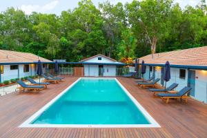 a swimming pool on a wooden deck with lounge chairs at Birch Resort Port Douglas in Port Douglas