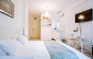 a white bedroom with a white bed and a kitchen at Apartment Marinis in Split