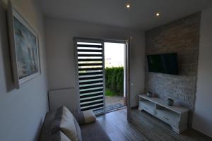 a living room with a sliding glass door with a television at Darłówko Apartament Morski III in Darlowko