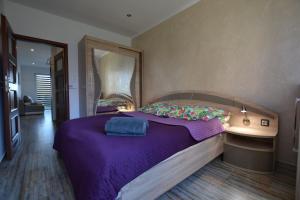 a bedroom with a purple bed and a mirror at Darłówko Apartament Morski III in Darłówko