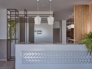 a lobby with a white counter with potted plants at Hotel St.John Suites Adults Only in Tsilivi