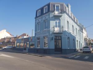 un bâtiment bleu et blanc au coin d'une rue dans l'établissement Hotel Des Arts, à Wimereux