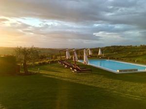 a swimming pool with chairs and umbrellas in a field at Villa il Castagno Wine & Resort in Siena