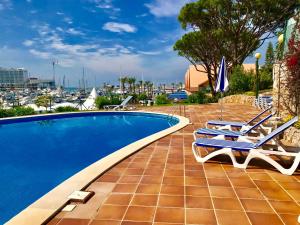 a swimming pool with two lounge chairs and an umbrella at Marina Garden by Ethnic Ocean in Vilamoura