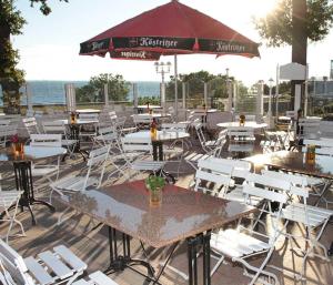 un patio con tavoli, sedie e ombrellone di Pension Radke a Heringsdorf