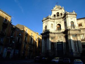 a tall white building with cars parked in front of it at B&B Bianca in Catania