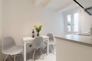 a white kitchen with a white table and white chairs at Masai - One bedroom flat 1st floor by train station in Florence