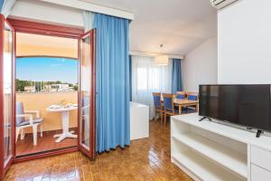 a living room with a large television and a dining room at Maistra Select Riva Apartments in Vrsar