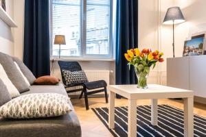 a living room with a couch and a table with flowers at No.3 Apartment Link-To-Happiness in Klaipėda