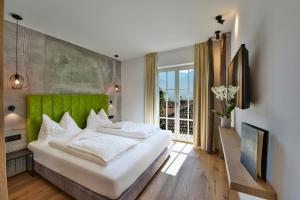 a bedroom with a large bed with a green headboard at Hotel Goldene Traube in Termeno