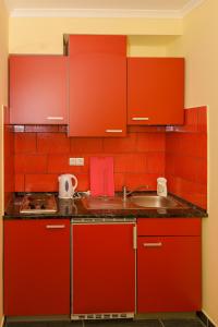 una cucina rossa con lavandino e armadi rossi di Rózsa Völgy Apartman a Eger