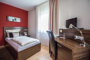 a bedroom with a bed and a desk with a computer at Landhotel Wolfschlugen in Wolfschlugen