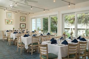 a dining room with white tables and chairs and windows at The Carroll Villa Hotel in Cape May