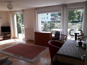 a living room with a table and a large window at Résidence Le Parc COLMAR in Colmar