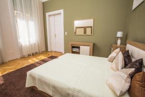 a bedroom with a large white bed with a mirror at Novák apartman Szeged in Szeged