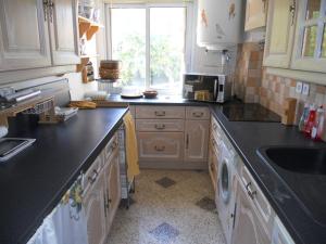 cocina con encimera negra y fregadero en Le GALOUBET, en La Ciotat