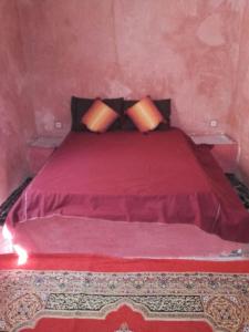 a red bed with two pillows in a room at Auberge Toda in Aït Igad