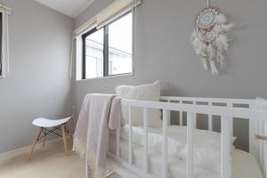 a white crib in a white room with a window at Condominium Mahalo in Chatan