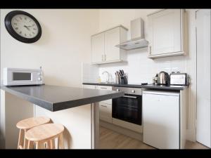 a kitchen with a counter and a clock on the wall at Cedar Apartment in Helensburgh