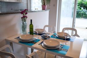 a table with plates and glasses and a bottle of wine at Apartments Stasic in Vrbnik
