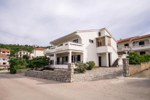 a white house with a stone wall at Apartments Stasic in Vrbnik