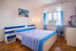 a bedroom with a blue and white bed and a window at Apartments Stasic in Vrbnik
