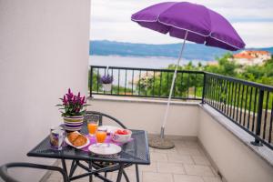 a table with breakfast food and an umbrella on a balcony at Apartments Stasic in Vrbnik