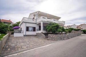 a white house with a stone retaining wall at Apartments Stasic in Vrbnik