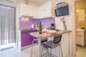 a kitchen with purple cabinets and a table with stools at Apartments Stasic in Vrbnik