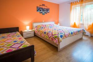 a bedroom with two beds and an orange wall at Apartments Stasic in Vrbnik
