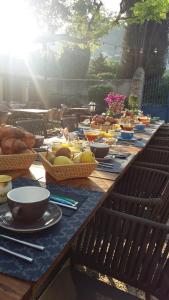 una larga mesa de madera con tazones de comida. en La Bastide Bleue en Séguret