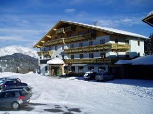 un gran edificio con coches aparcados en la nieve en Innviertler Berggasthof, en Radstadt