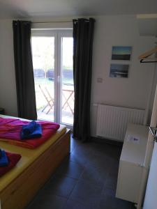 a bedroom with a bed and a sliding glass door at Piratennest- Kojen in Dranske