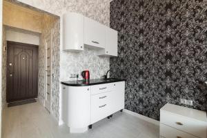 - une cuisine avec des placards blancs et du papier peint noir et blanc dans l'établissement Apartment on Dudayeva 17, à Lviv