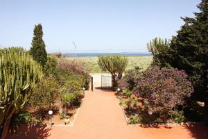 a red brick walkway with trees and flowers at TONNARA84 in San Vito lo Capo