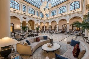 un gran vestíbulo con sofás y mesas en un edificio en Gran Hotel Miramar GL, en Málaga