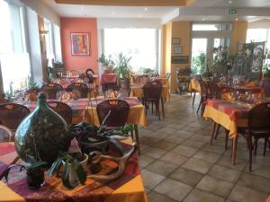 un restaurante con mesas y sillas con plantas. en Hôtel aux Bruyères en Orbey