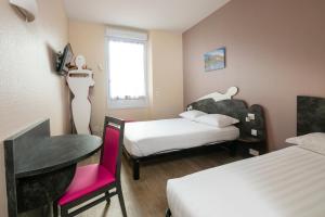 a room with two beds and a table and a chair at L'Esterel in Cannes