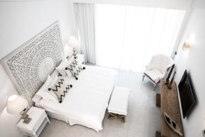 a white bedroom with a white bed and a chair at Abaton Island Resort & Spa in Hersonissos