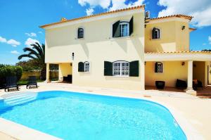 una villa con piscina frente a una casa en Suites & Beds DP Albufeira, en Albufeira
