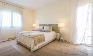 a white bedroom with a large bed and a window at Suites & Beds DP Albufeira in Albufeira
