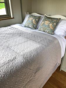 a bed with a white bedspread and pillows on it at Luxury Shepherds Hut in Bransgore