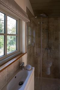 a bathroom with a shower and a sink and a window at Luxury Shepherds Hut in Bransgore