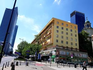 a tall yellow building on a city street with buildings at Premium Key-Apartaments Śródmieście in Warsaw