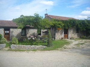 una antigua casa de piedra con árboles y flores en la raymondiere, en Vernoux-en-Gâtine
