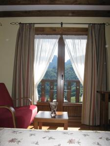 a bedroom with a large window and a red chair at La Posada de Cucayo in Dobres